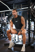 Man wearing the washed-black S20 End of Summer Vest, front view, seated — drop-armhole cut with small white S20 chest mark